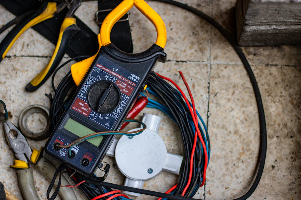 Electrician's meter, pliers and coiled wire on a job site floor